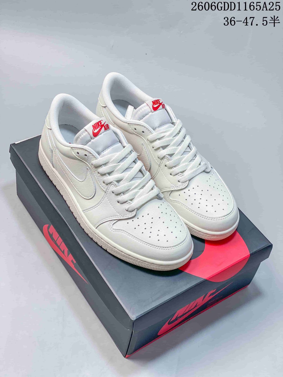 Pair of white low-top Jordan 1 sneakers with red tongue branding, displayed on a shoebox.