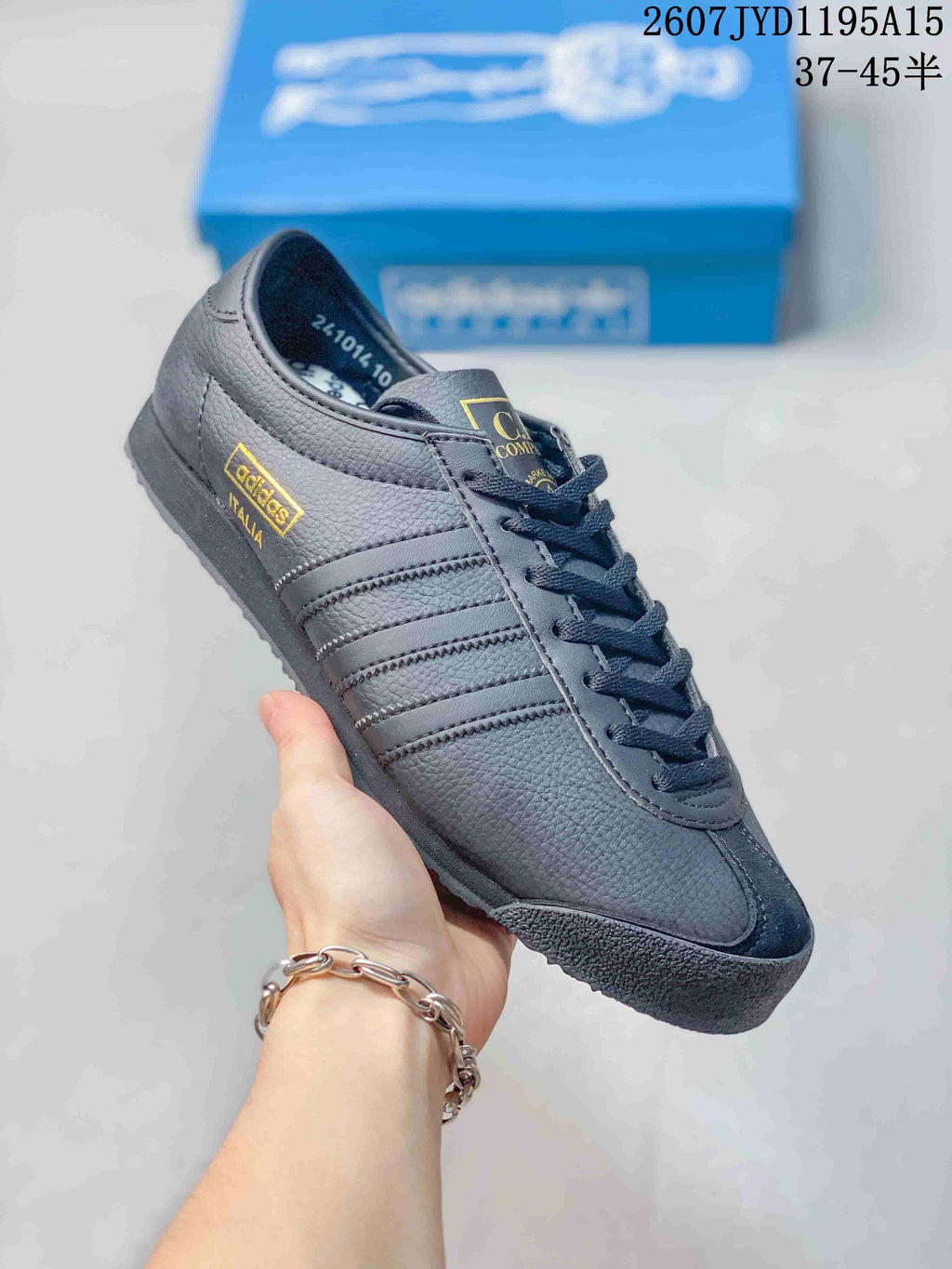 Angled side view showing the textured dark gray upper, gold adidas Italia side mark, tonal stripes, and black outsole.