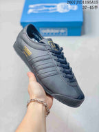 Angled side view showing the textured dark gray upper, gold adidas Italia side mark, tonal stripes, and black outsole.