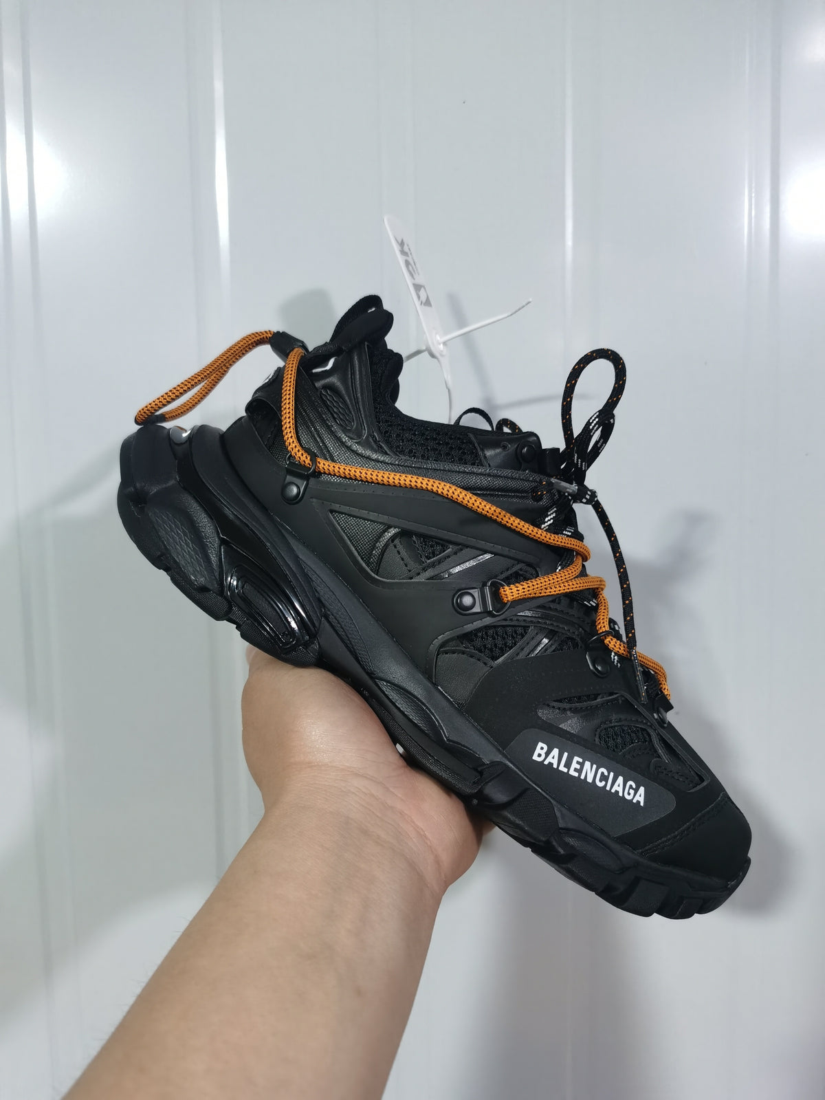 Front three-quarter view showing the black sneaker's layered upper, contrasting laces, mesh sections, and Balenciaga branding.