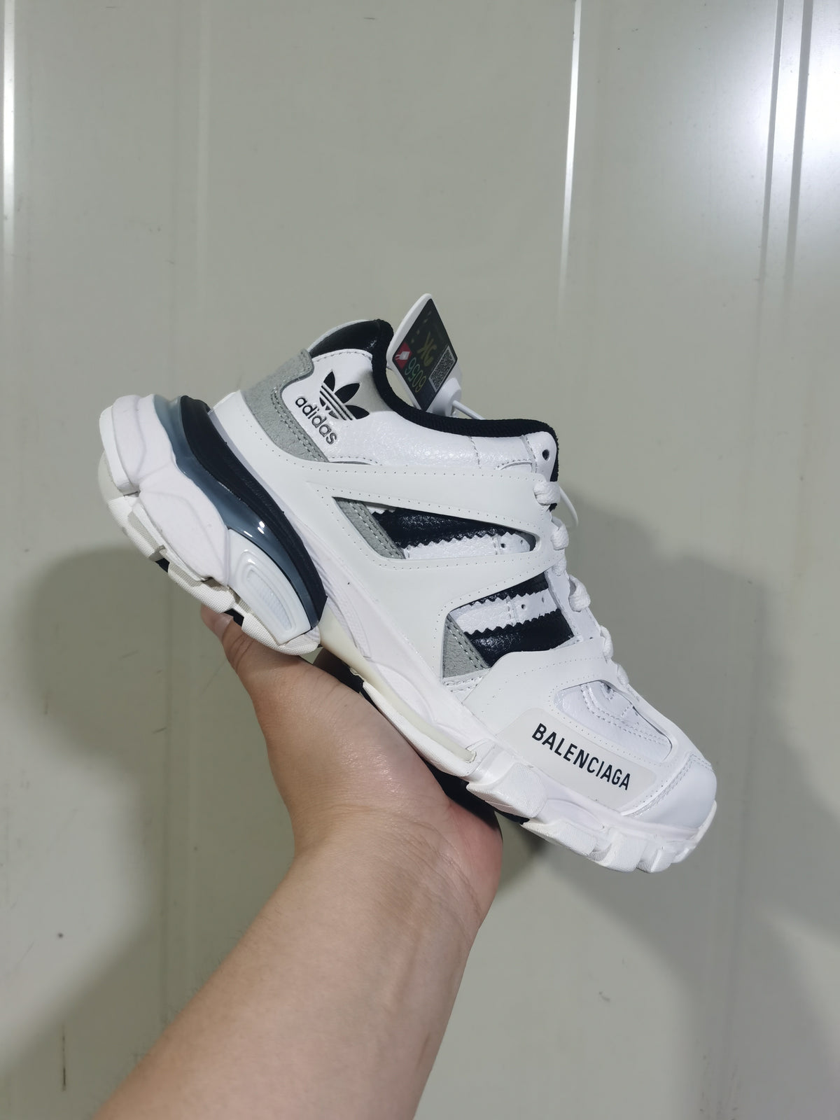 Angled view of the white and black sneaker showing Balenciaga toe branding, adidas trefoil detailing and the chunky outsole.