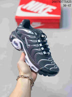 Angled side view of the black and white Nike Air Max Plus TN sneaker showing the layered upper and visible cushioning windows.