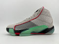 Side view of a grey Jordan Luka 1-style high-top basketball shoe with green sole accents, red trim, and a black speckled midsole.