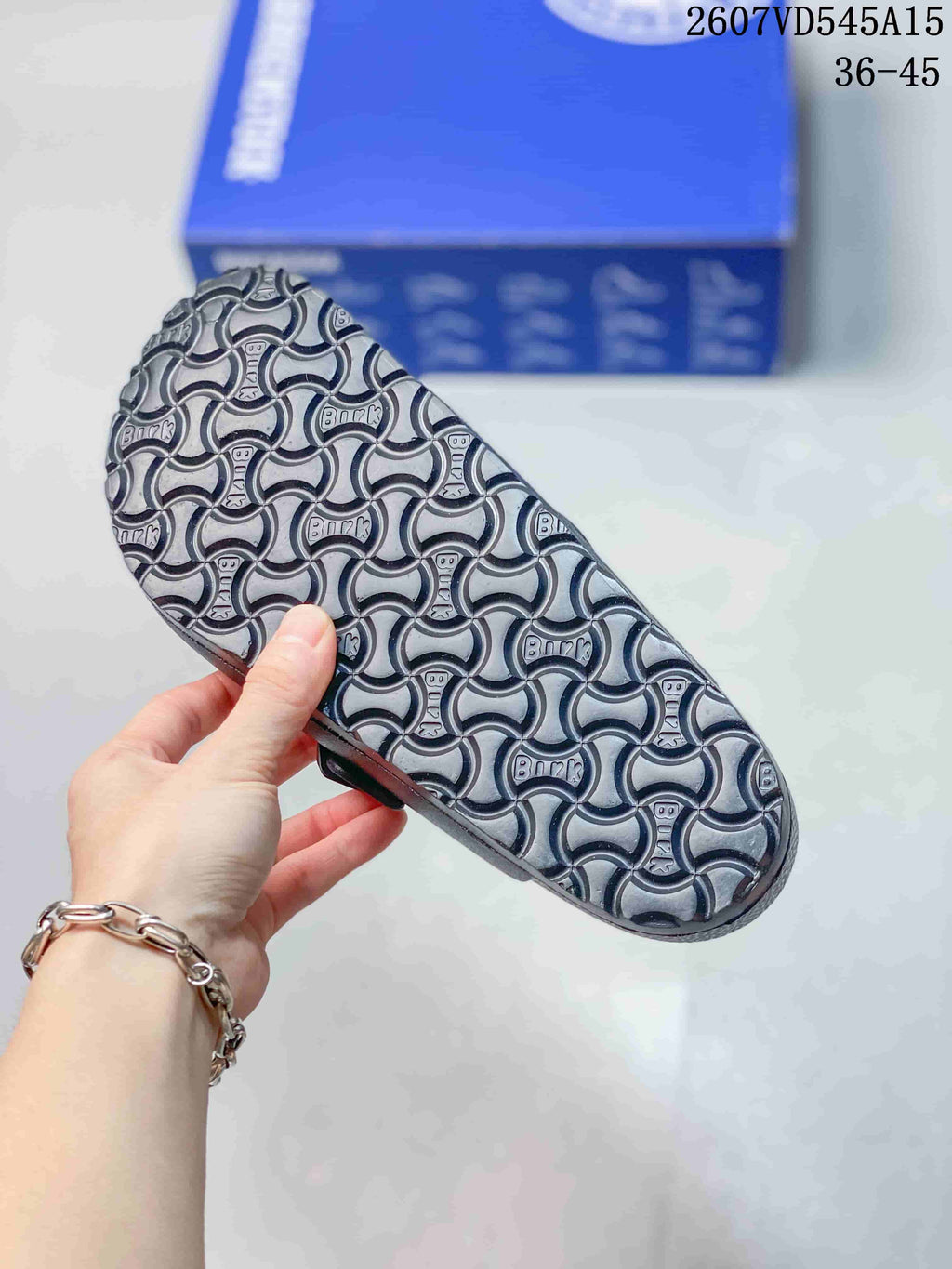 Close view of the sandal outsole showing a repeating raised pattern and branding details.