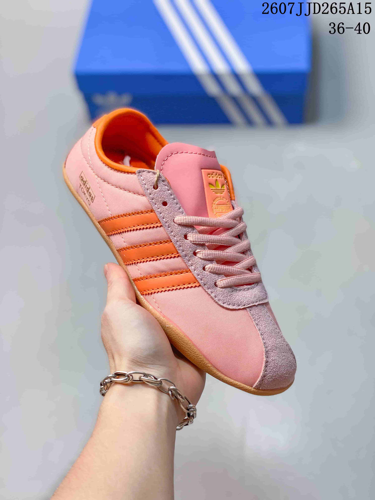Angled side view of a pink and orange adidas Tokyo sneaker with three orange stripes and gum-colored outsole.
