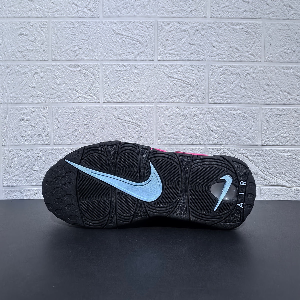 Outsole view of a black Nike sneaker with a light-colored swoosh