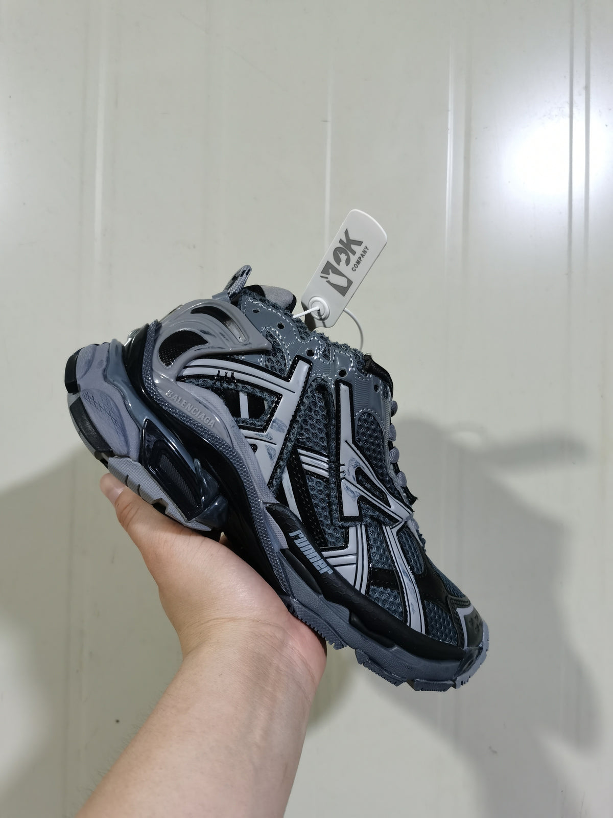 Close angled view of the dark grey and black Balenciaga Runner sneaker showing its layered overlays, mesh panels, laces, and chunky sole.
