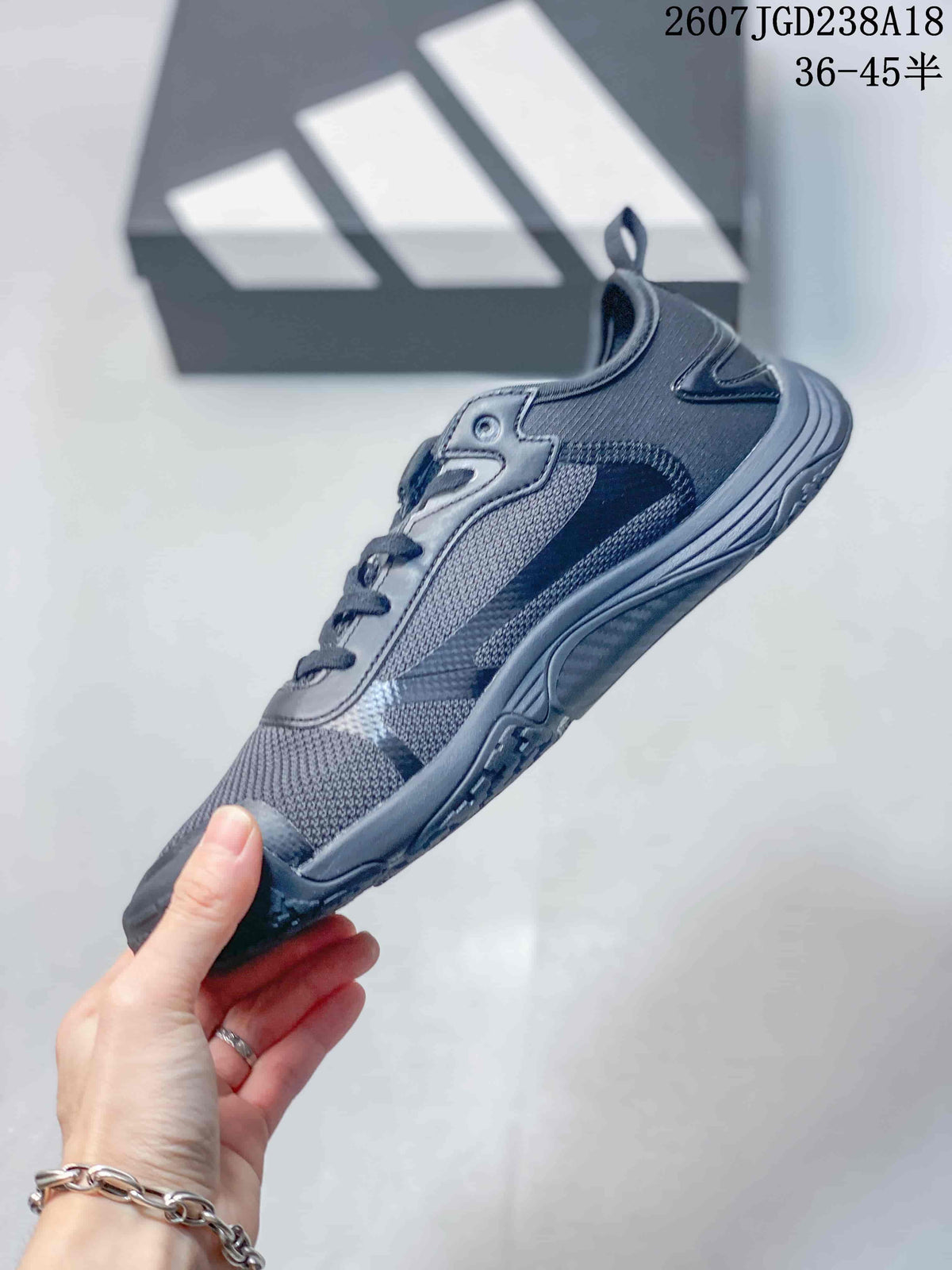 Side view of the dark gray adidas sneaker showing its low-profile shape, mesh-look panels, and layered upper.