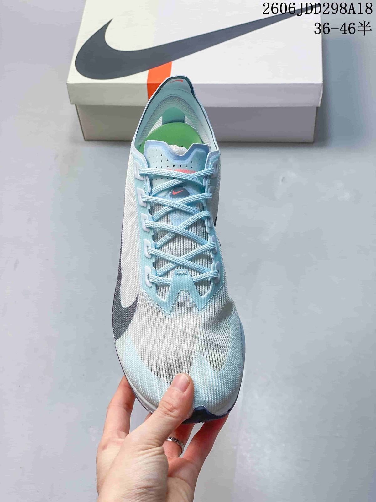 Top view of the shoe showing the lace configuration, perforated tongue, pale blue upper, and dark side branding.