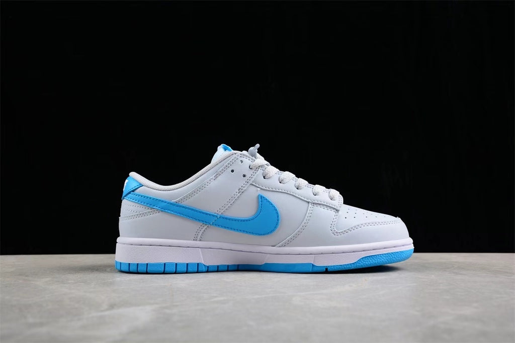 Side profile of the low-top sneaker showing the gray and white upper, bright blue Swoosh, white midsole, and blue outsole.