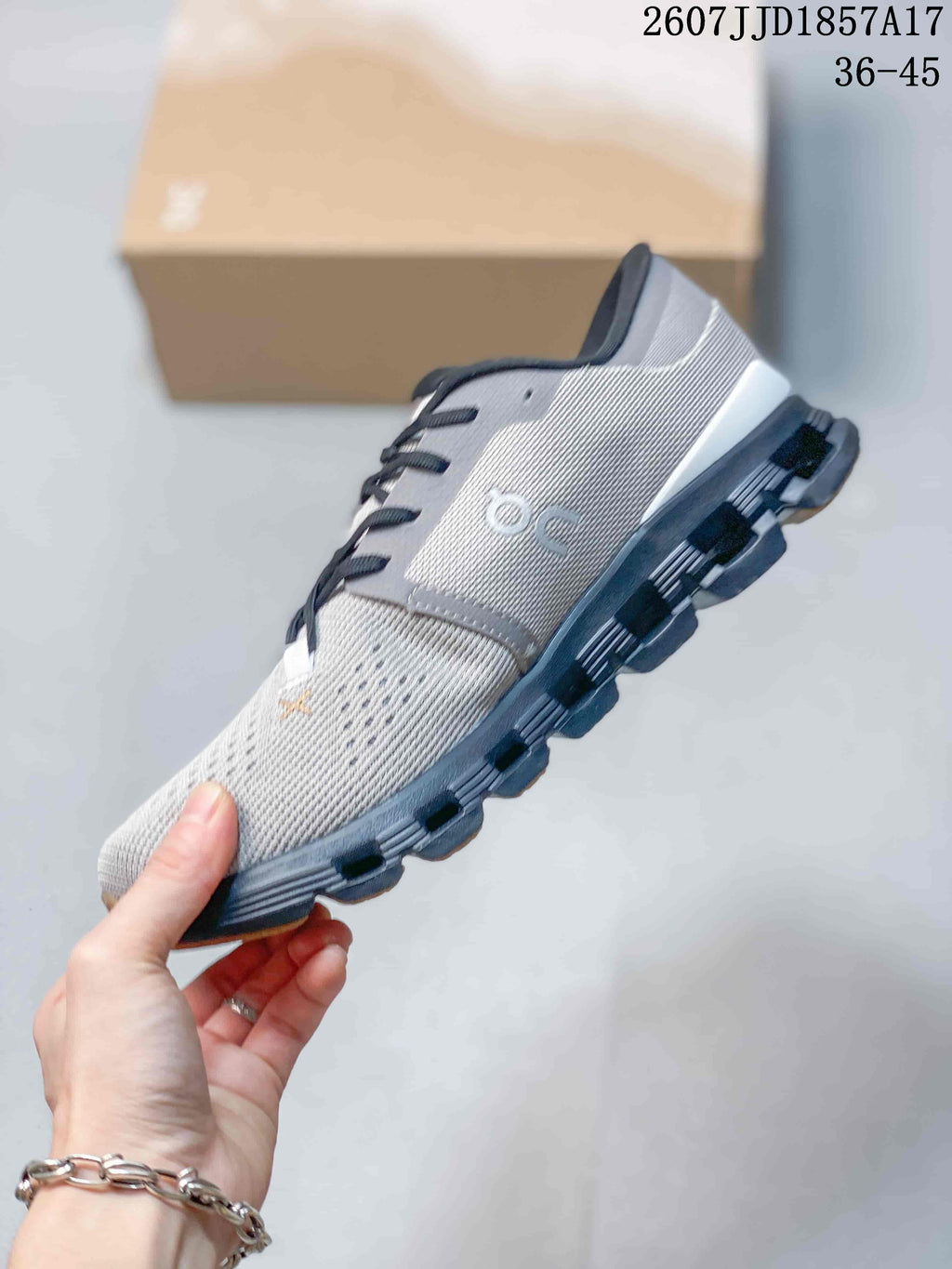 Side profile of a gray and black On sneaker showing the knit-style upper, dark overlays, and segmented sole.