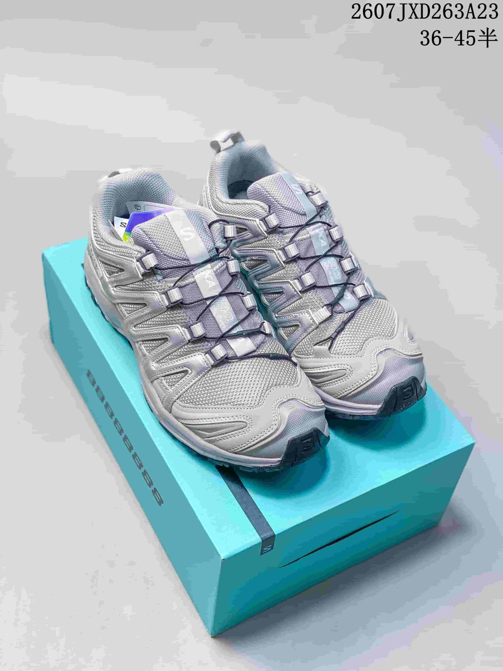 Pair of alloy gray and silver Salomon XA Pro 3D sneakers displayed on a turquoise shoe box; style code and size range text appear at the top right.