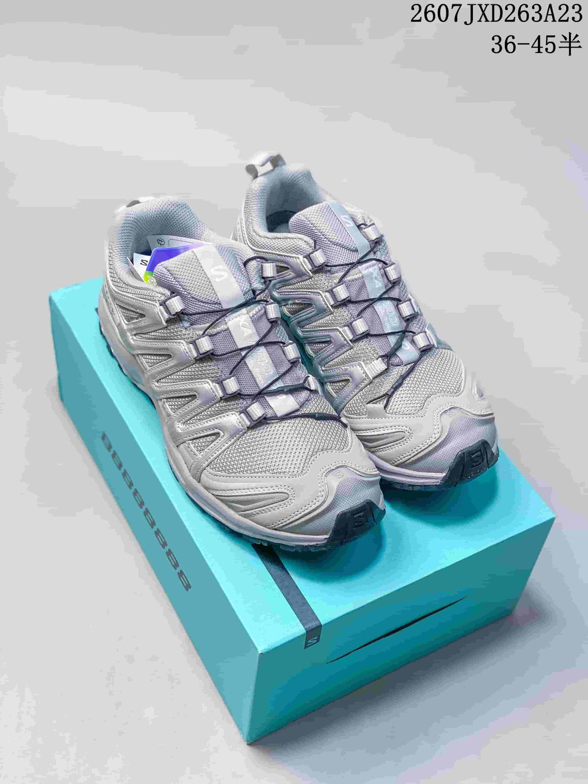 Pair of alloy gray and silver Salomon XA Pro 3D sneakers displayed on a turquoise shoe box; style code and size range text appear at the top right.
