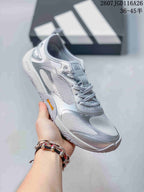 Angled side view of a silver gray adidas Groundflow sneaker showing the woven-texture upper and layered overlays