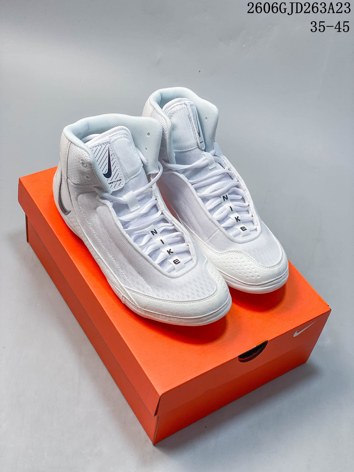 White Nike Inflict 4 wrestling shoes with clean, unpatterned side panels, shown on an orange shoe box.