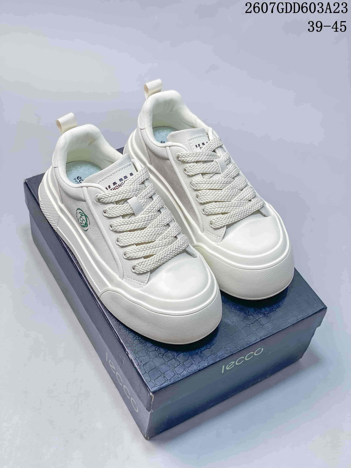 Pair of white ECCO low-top lace-up sneakers displayed on a branded shoe box; image text shows style code 2607GDD603A23 and size range 39–45.