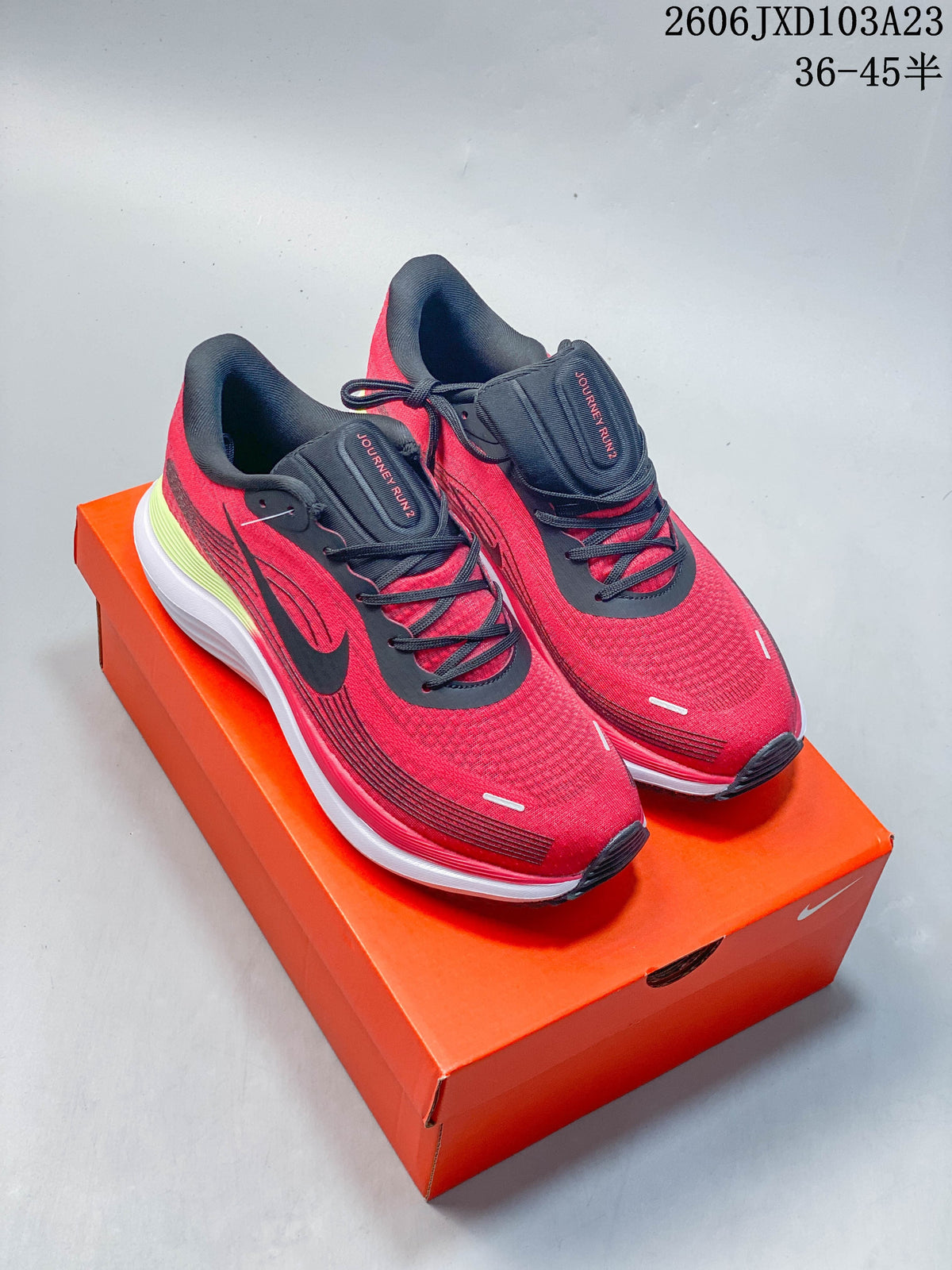 Pair of red and black Nike Air Zoom Pegasus running shoes displayed on an orange shoebox