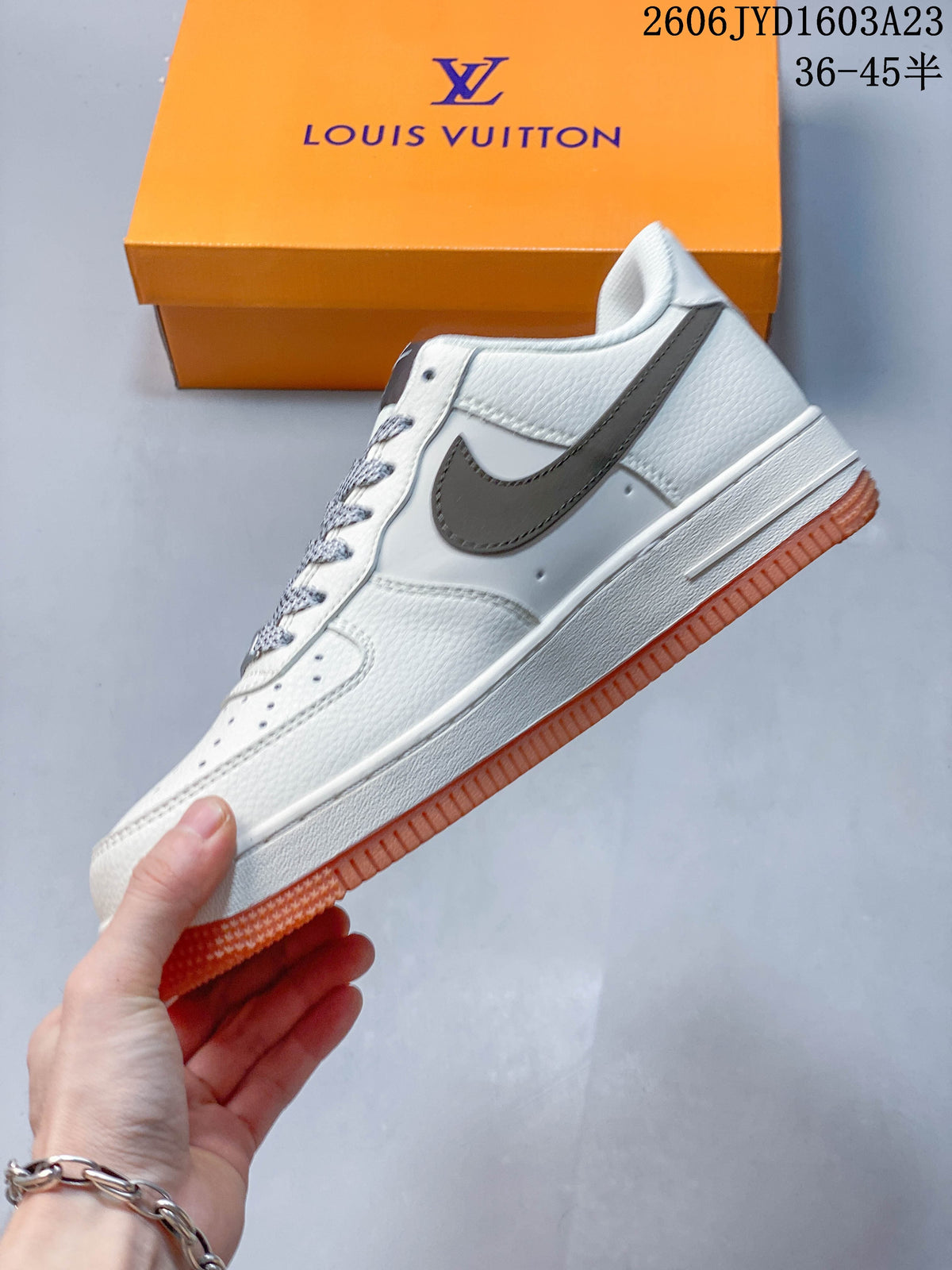 Side profile showing the white upper, gray-brown side accent, printed graphics, and gum-orange outsole