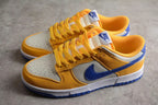 Pair of low-top Nike sneakers shown from an angled side view in wheat gold, white, and blue.