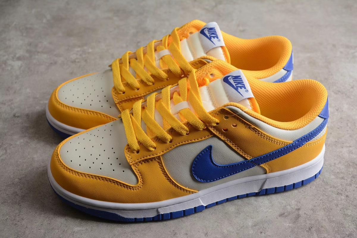 Pair of low-top Nike sneakers shown from an angled side view in wheat gold, white, and blue.
