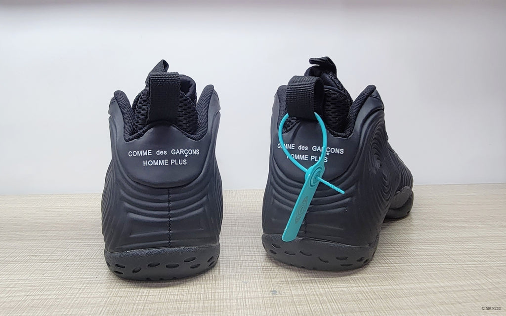 Rear view of black high-top sneakers with Comme des Garçons Homme Plus heel branding.