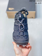 Front view of the sandal showing the open toe, layered straps, cord-style lacing, and dark mesh-like upper panels.