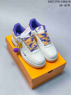 Pair of white Nike low-top sneakers with purple and gold details, displayed on an orange shoebox with a basketball accessory.