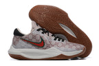 Light neutral-colored basketball shoe with repeating monogram-style graphics and a brown outsole.