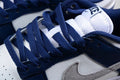 Close-up of navy laces, white tongue, navy overlays, and gray Swoosh on the sneaker.