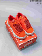 Pair of orange Nike low-top sneakers displayed on an orange Nike shoebox, with dark red laces and white midsoles.