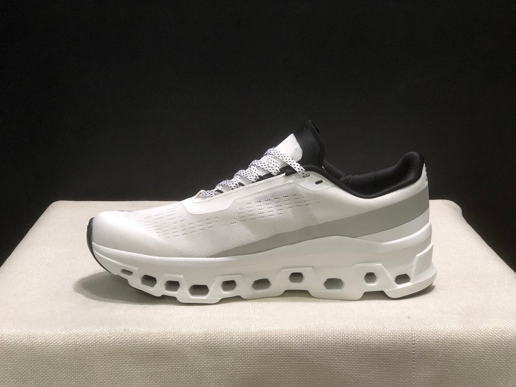 Lateral side profile of a white On Cloudmonster sneaker with a sculpted white sole and textured upper.