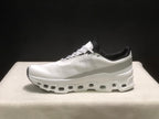 Lateral side profile of a white On Cloudmonster sneaker with a sculpted white sole and textured upper.