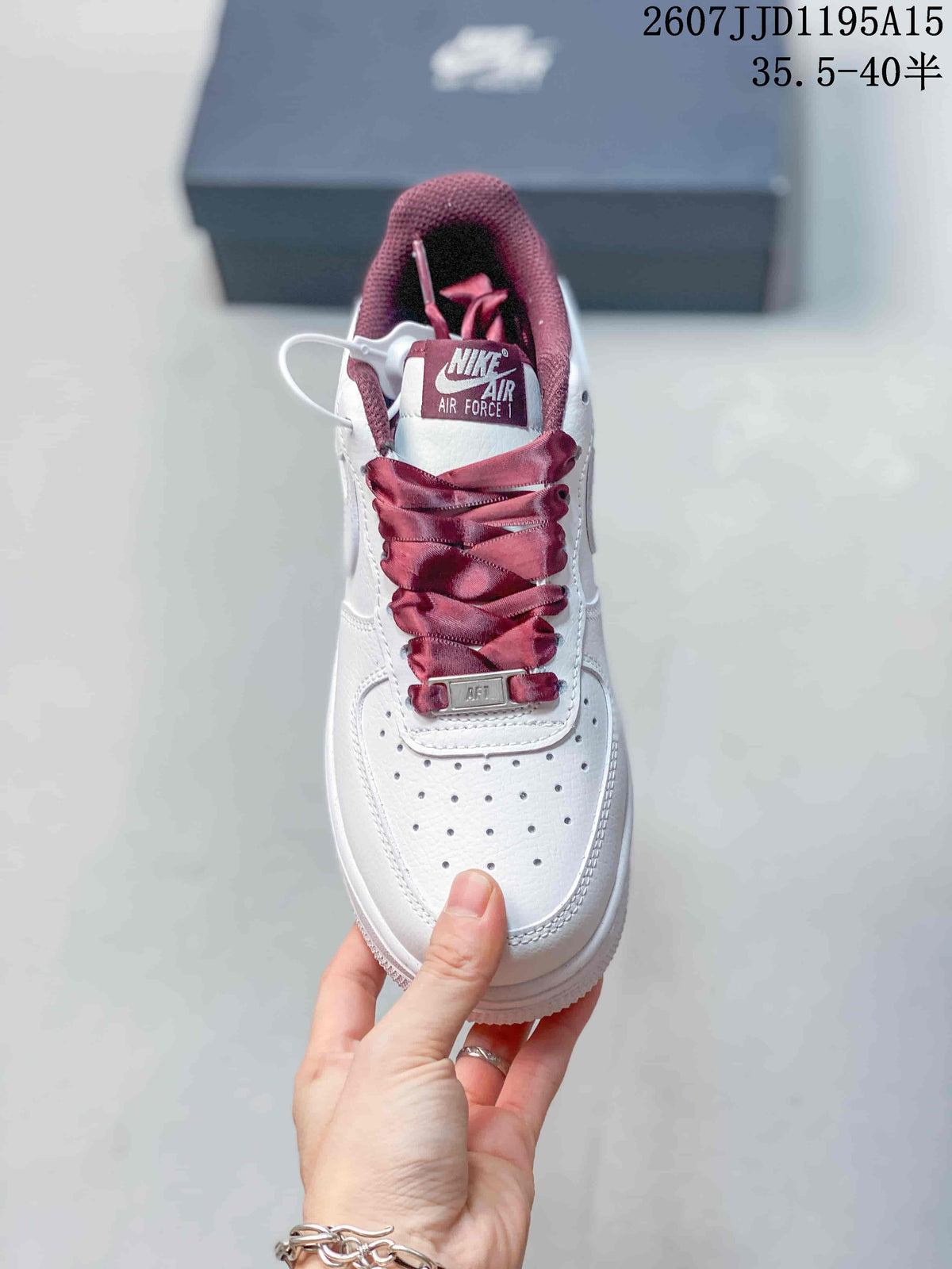 Top view of a white sneaker with a perforated toe box, burgundy laces, and Air Force 1 tongue branding.