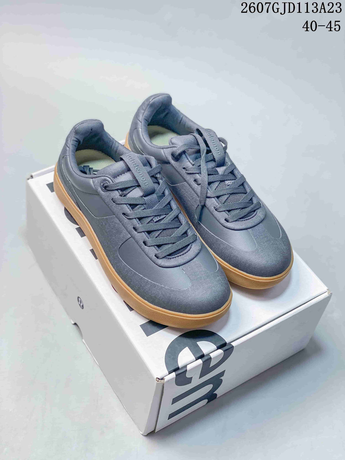 Pair of dark gray lululemon Cityverse sneakers with matching laces and gum-colored outsoles displayed on a shoebox; image text shows style code 2607GJD113A23 and size range 40–45.