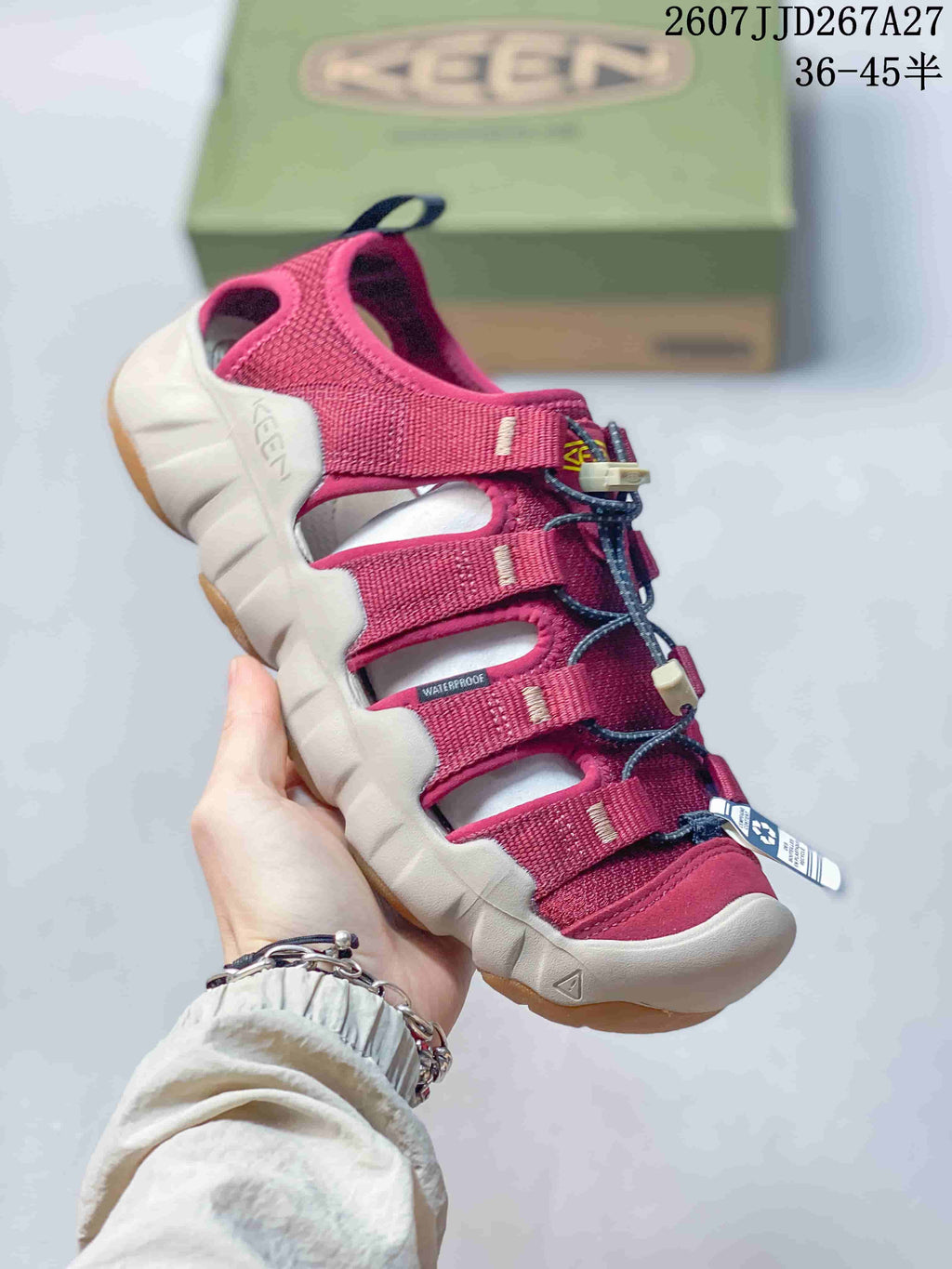 Angled side view of a burgundy KEEN sandal showing the open upper, adjustable straps, rear pull tab, and light-colored sole.