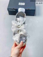 Front view of a silver sneaker with multiple sheer white bow laces.