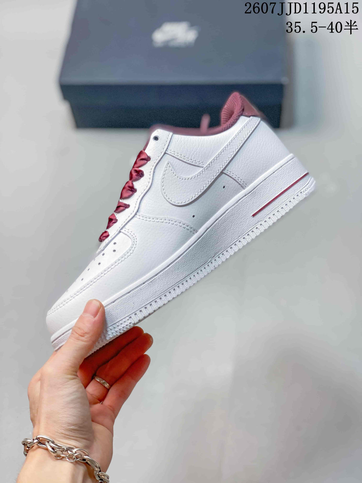 Side view of a white low-top sneaker showing the stitched Swoosh panel and burgundy collar accent.