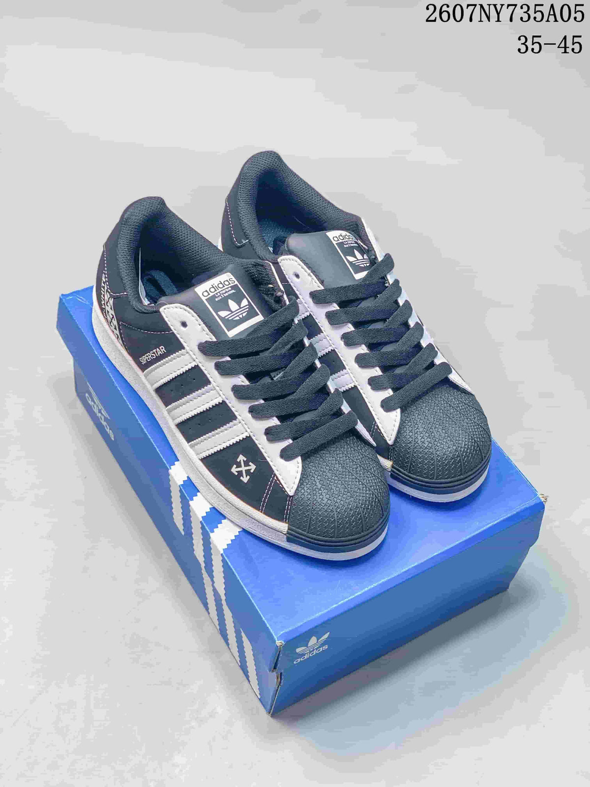 Pair of black and white Adidas Superstar sneakers displayed on a blue Adidas shoe box.