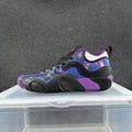 Side view of a black low-top sneaker with purple trim, vivid blue multicolor panels, and a sculpted outsole.