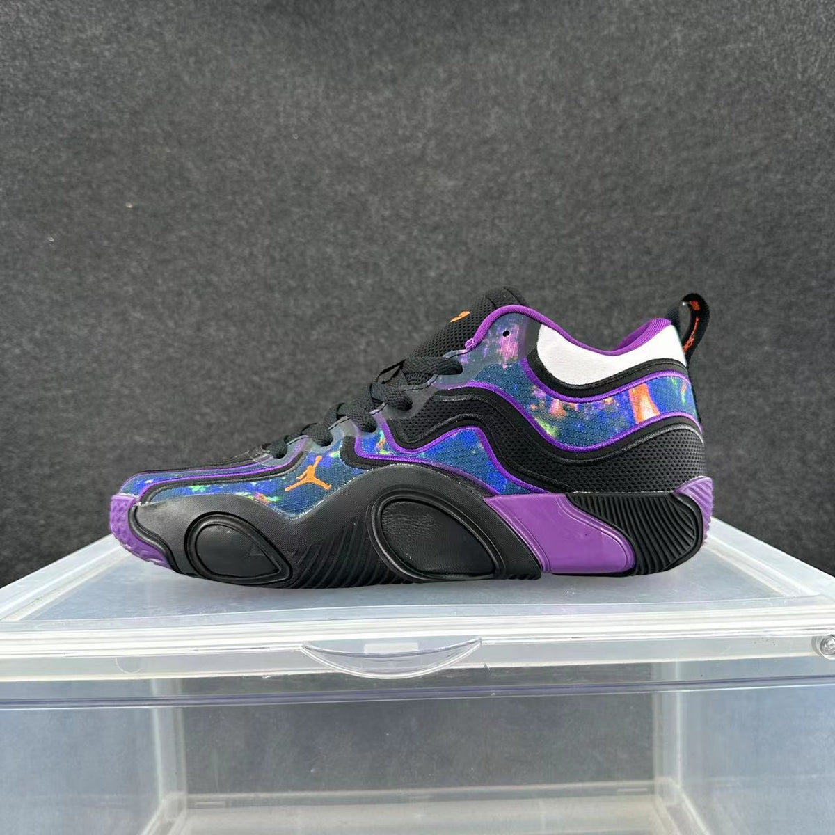 Side view of a black low-top sneaker with purple trim, vivid blue multicolor panels, and a sculpted outsole.