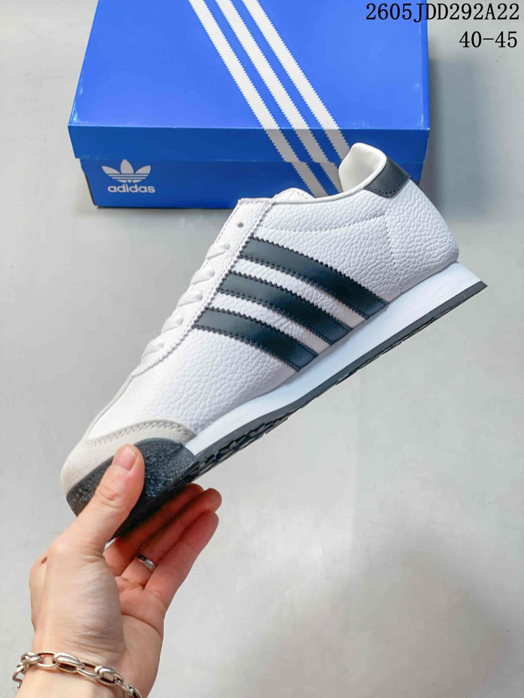 Side profile of the white and black low-top sneaker showing the three side stripes, lace-up design, and layered sole.