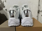Rear view of white Nike NOCTA Glide sneakers with reflective silver-tone heel details.