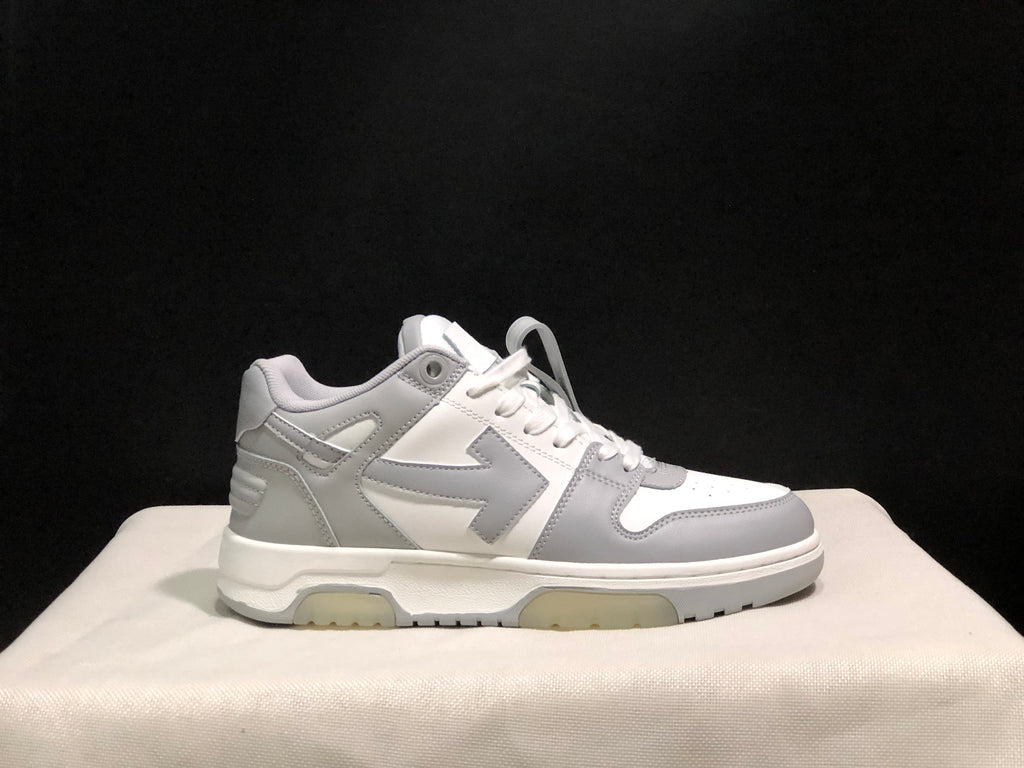 Clean side profile of one white and gray low-top sneaker against a dark background.