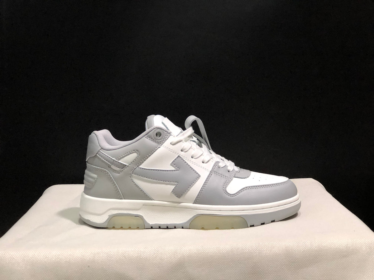 Clean side profile of one white and gray low-top sneaker against a dark background.