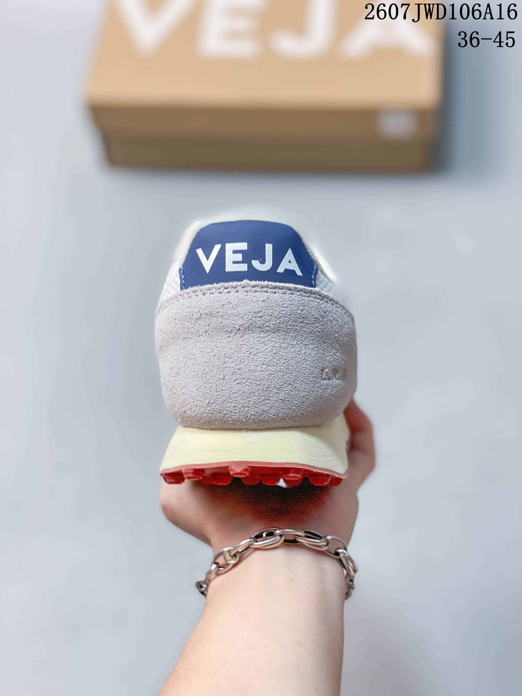 Rear view of a VEJA sneaker showing the white heel, blue tongue detail, cream midsole, and red outsole.