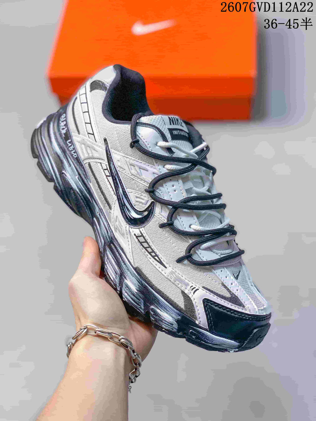 Angled side view of the white and black sneaker showing the layered upper, dark laces, Nike Swoosh, and textured sole.
