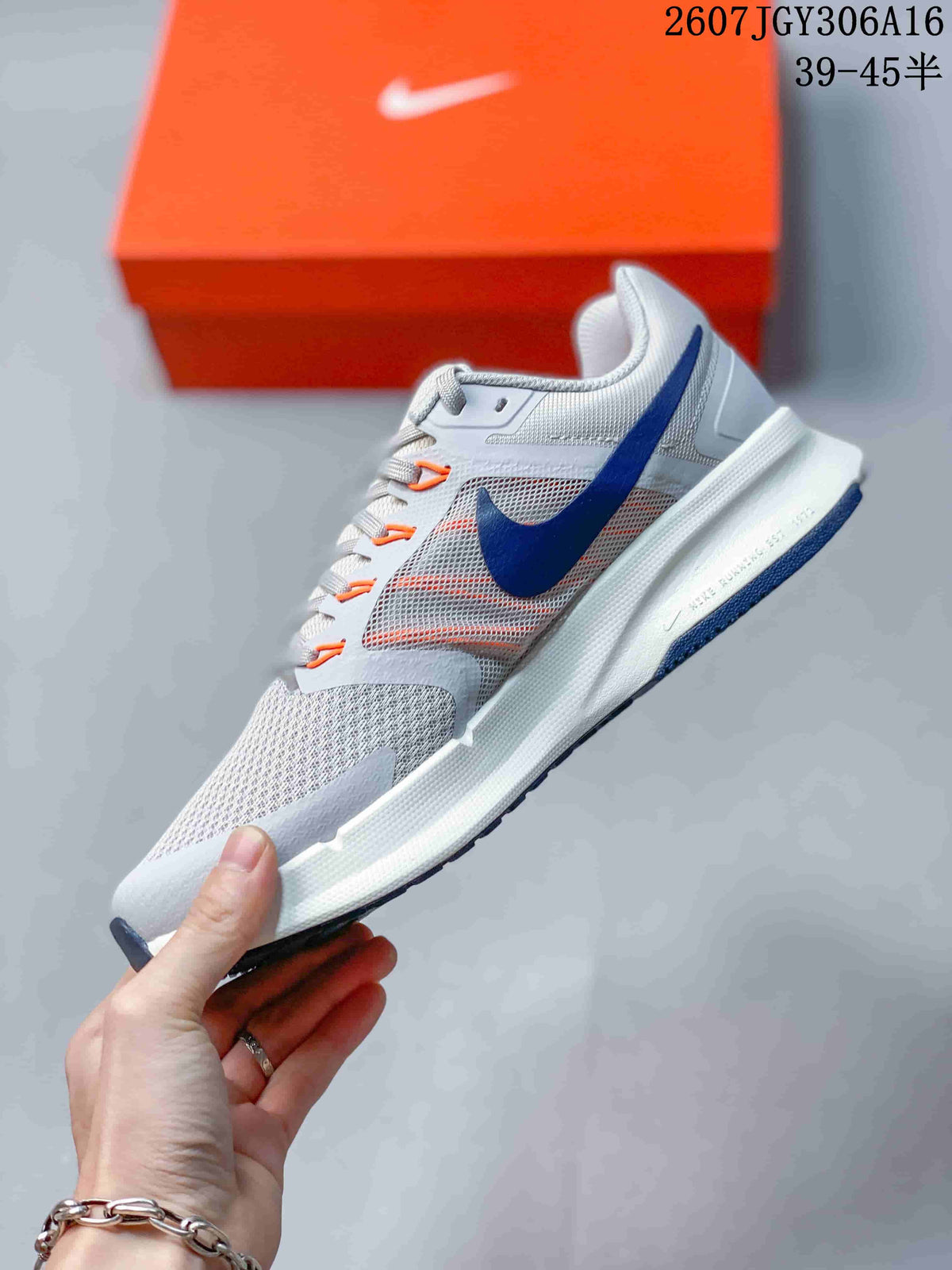 Side view showing the gray mesh-like upper, navy Nike Swoosh, orange accents and white midsole.