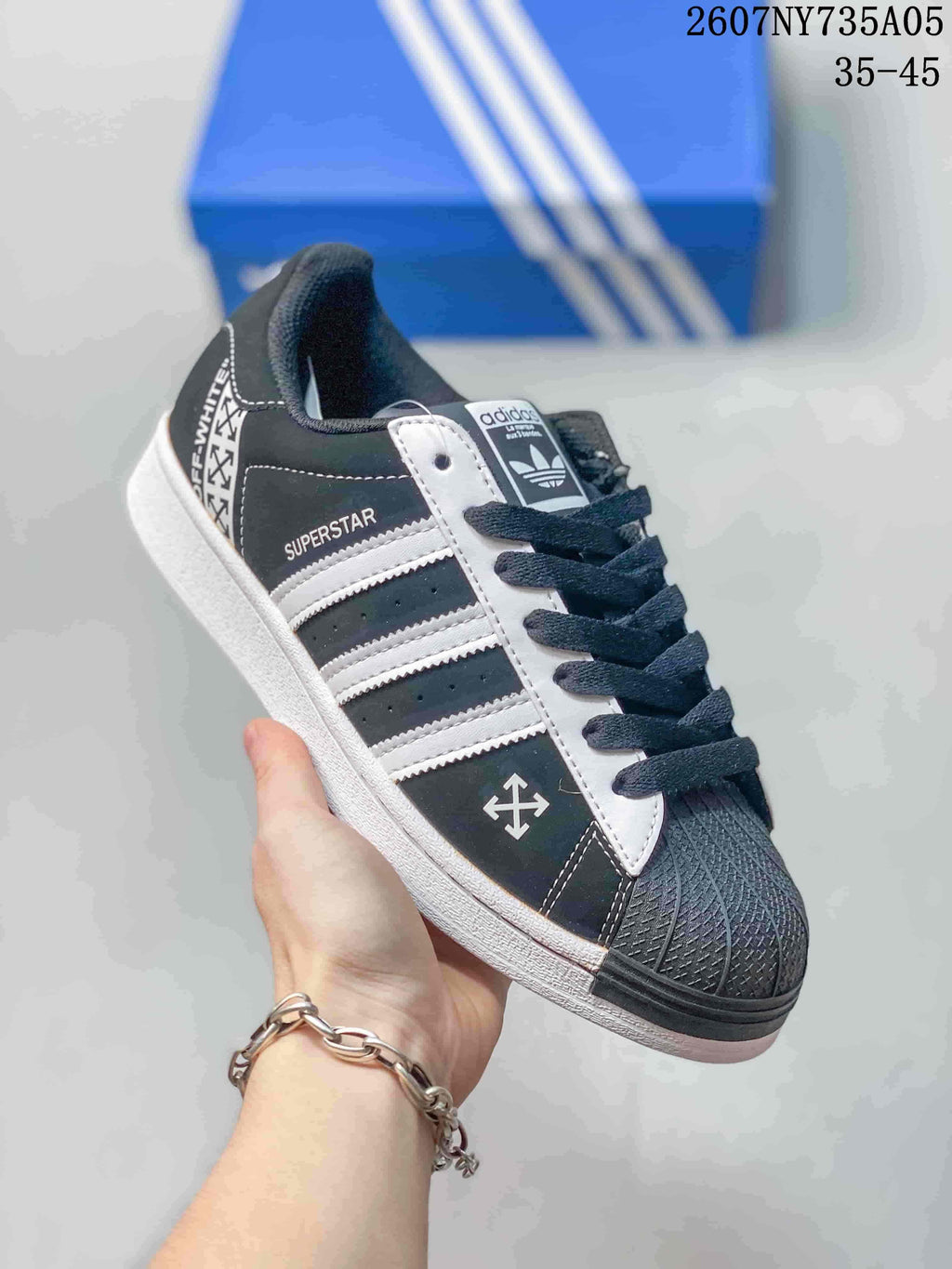 Angled side view showing the Superstar side label, three white stripes, textured toe, and black-and-white colorway.