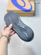 Close view of the textured outsole on a black ASICS running shoe, showing segmented tread and sculpted grooves.