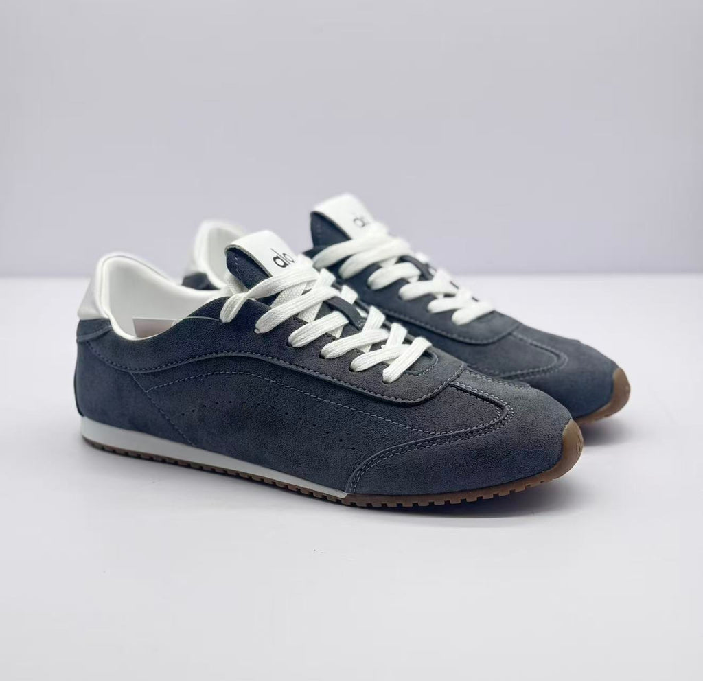 Three-quarter front view of the carbon gray Alo sneakers with white laces and contrasting collars.